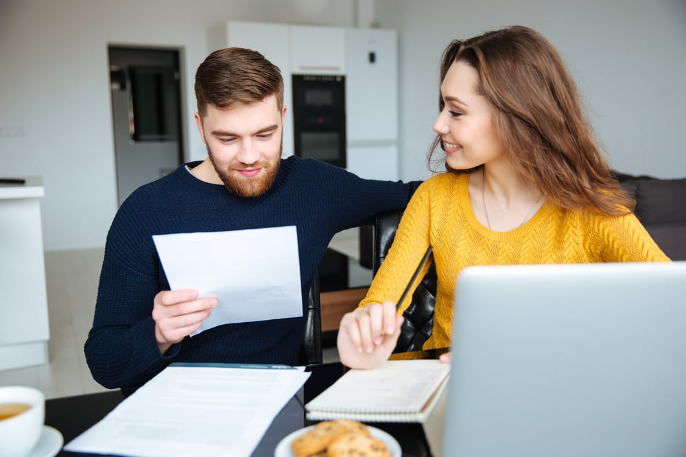 Happy young couple reviewing their flood policy at home